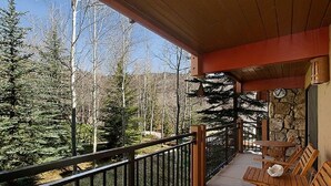 A balcony with a wooden railing, a stone wall, and a clock. - 715 Stonebridge Condos Slopeside Western Decor Full Kitchen (Snowmass Village)