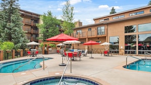 A hotel pool area with multiple pools, outdoor seating, and umbrellas. - 715 Stonebridge Condos Slopeside Western Decor Full Kitchen (Snowmass Village)