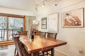 A dining area with a wooden table, wicker chairs, and artwork on the walls.