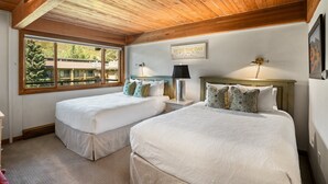 Une chambre avec deux lits, un plafond en bois, une grande fenêtre et une citation inspirante sur le mur.