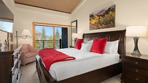 Una camera da letto con un letto grande, una cassettiera, una sedia, un balcone con vista e un quadro appeso al muro.