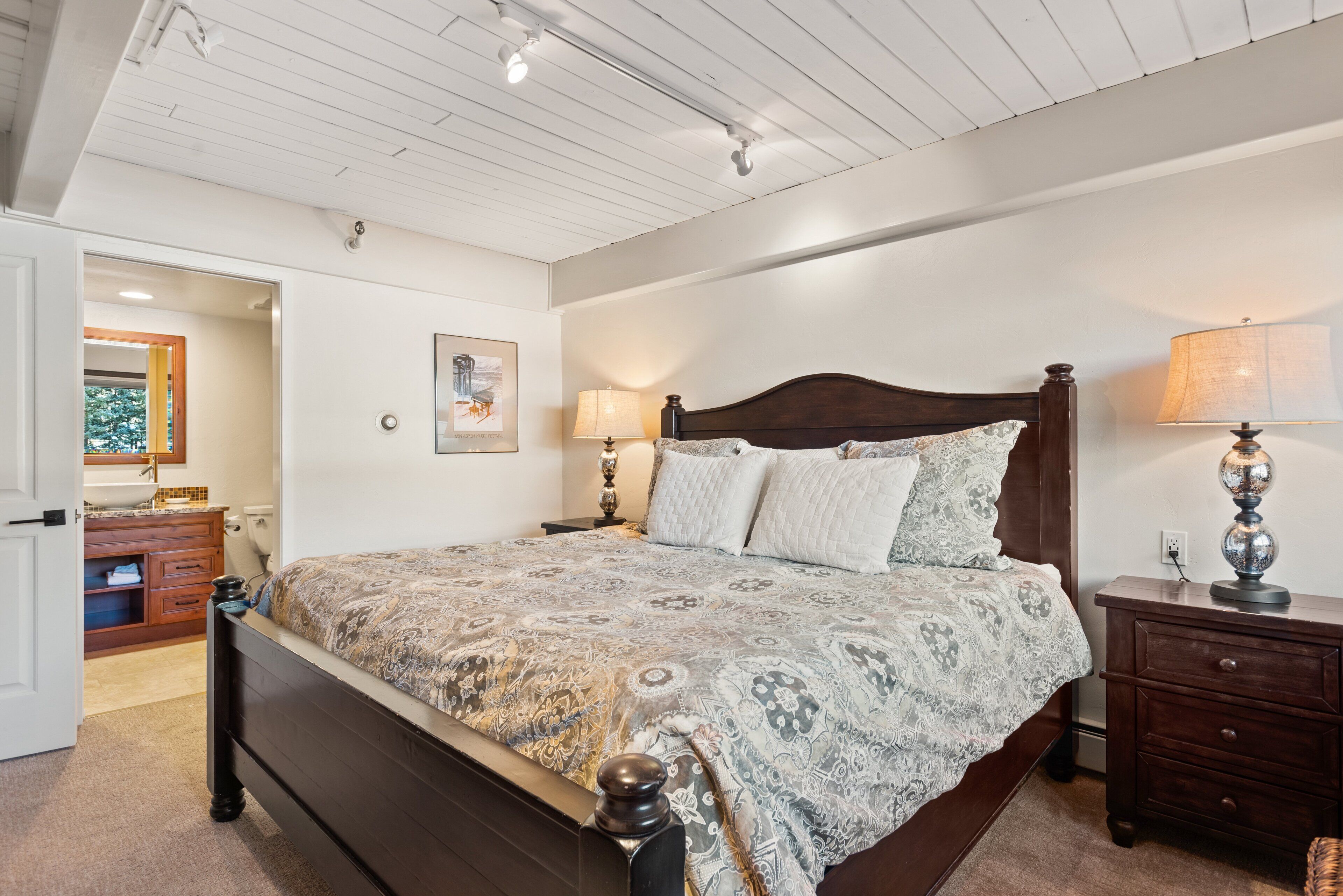 Una camera da letto con un letto grande, una testiera in legno, due abat-jour, un comodino e una cassettiera.