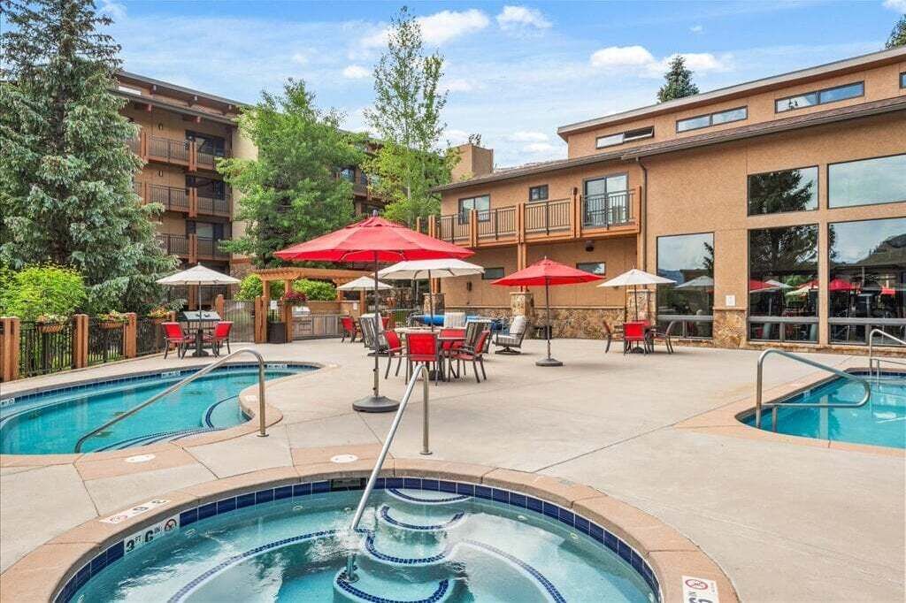 A pool area with multiple pools, outdoor seating, and umbrellas.