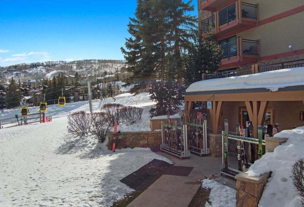 A ski resort entrance with a building, ski lift, and snow-covered ground.