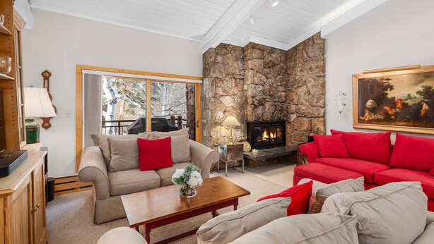 A living room with a stone fireplace, a beige sofa, a red sofa, and a wooden coffee table. - Stonebridge Condo 729, 1 Bdrm and Loft, W/D, Slopeside (Snowmass Village)