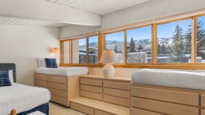 Une chambre dotée d’une grande fenêtre, de meubles en bois et offrant une vue sur un paysage enneigé.