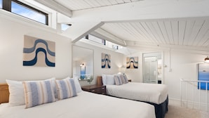 A bedroom with two beds, a large mirror, and artwork on the walls.