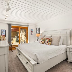 Classic bedroom with a large bed, nightstands, and a window offering a view of the outdoors.