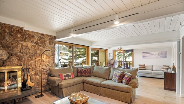 A cozy living room with a stone fireplace, a sectional sofa, and a glass coffee table. - On the Slopes, Recent Upgrades, Stonebridge Condo #935, Steps to Base Village (Snowmass Village)
