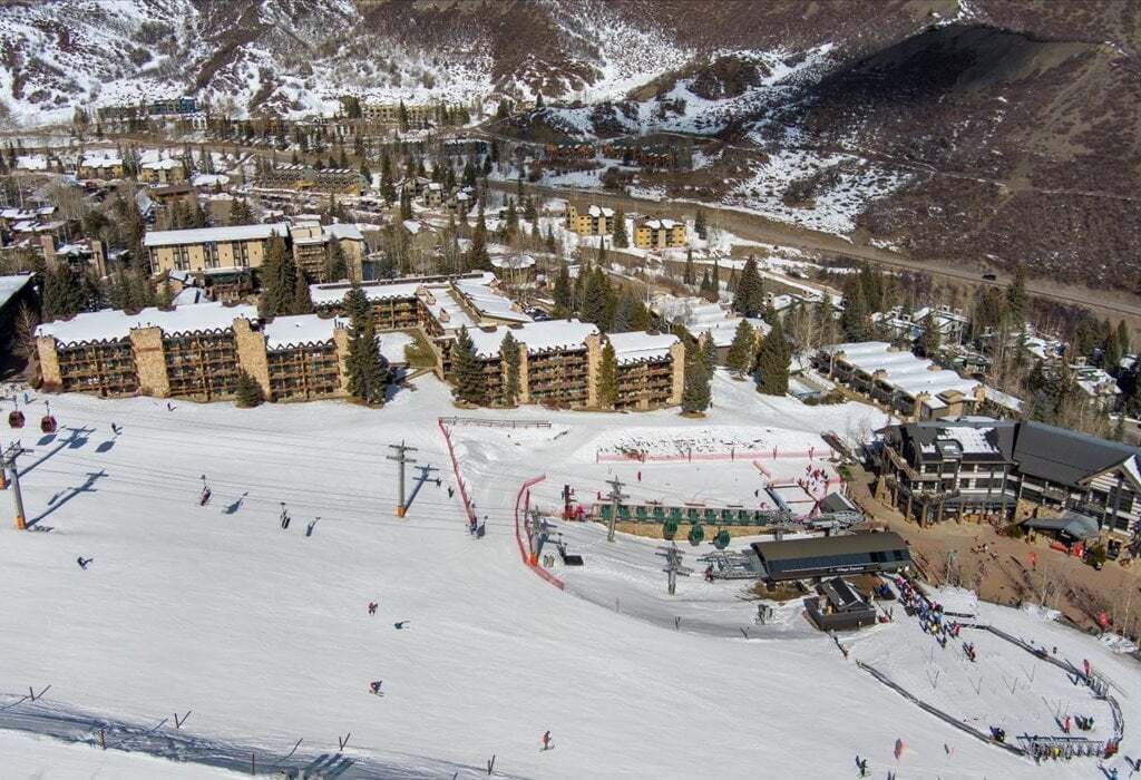 Une station de ski enneigée comprenant plusieurs bâtiments, des remontées mécaniques et une piste de ski.