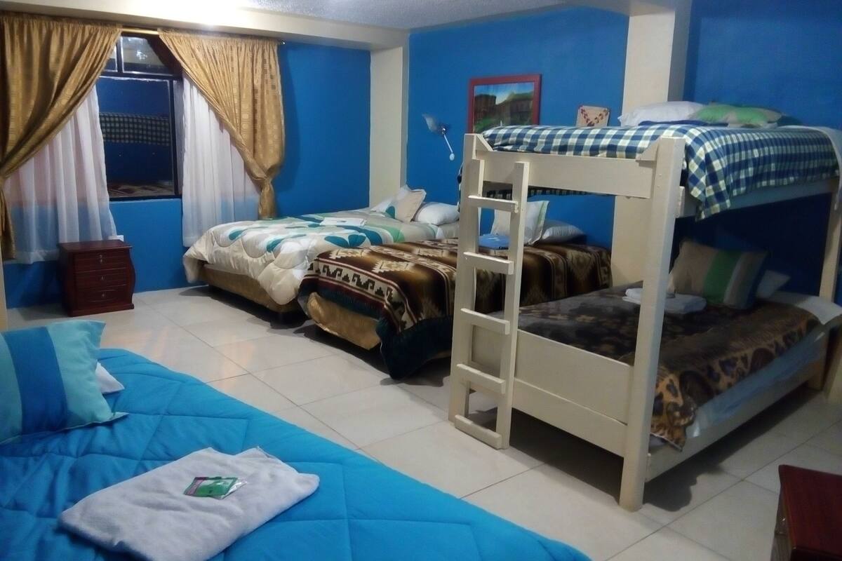 Una habitación con literas, una ventana con cortinas y un pequeño armario de madera.