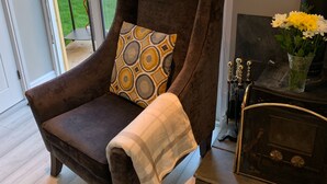Una sala acogedora con un sillón marrón, un cojín estampado y una manta blanca.