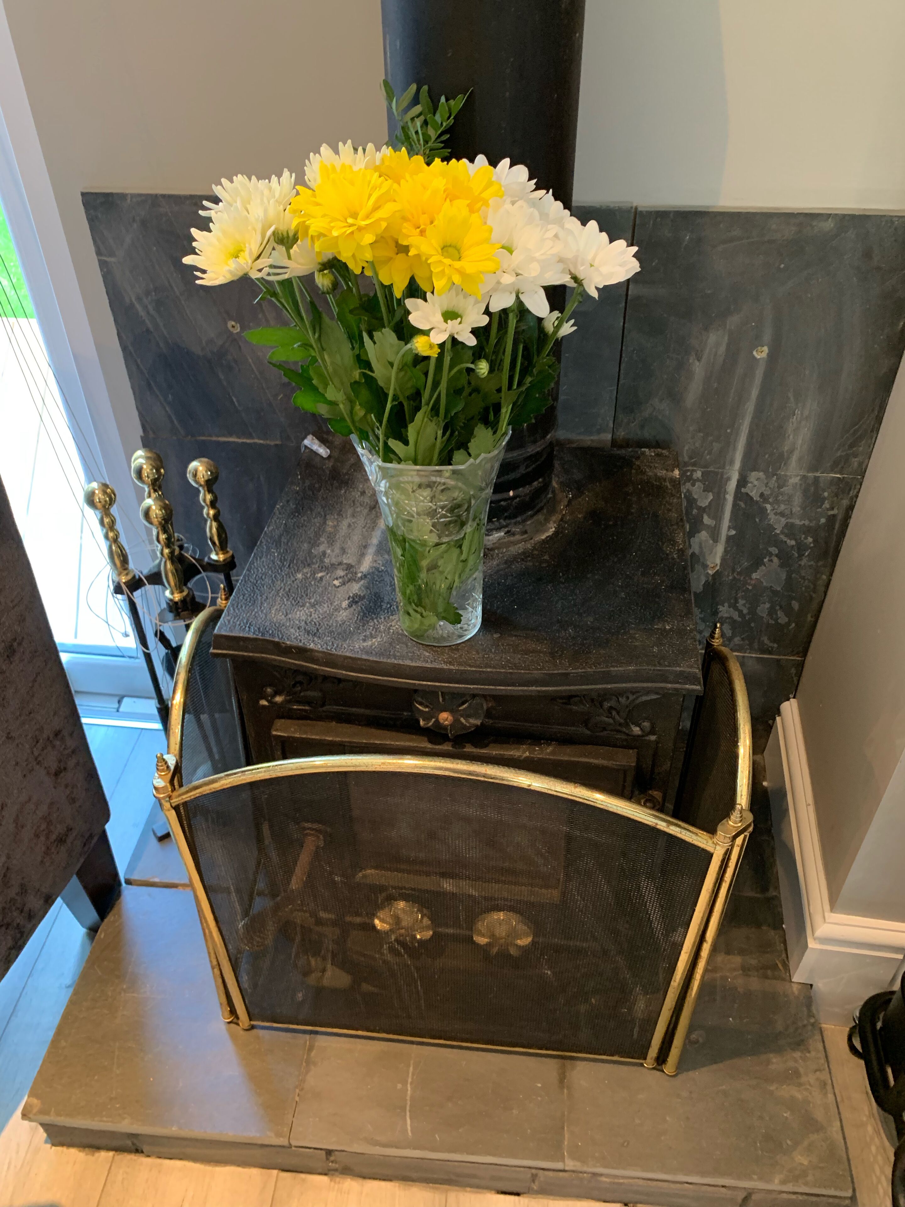 A fireplace with a vase of flowers on top.