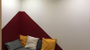 Un canapé d’angle avec un dossier rouge et des coussins jaunes et gris.