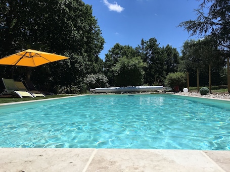 Una piscina al aire libre de temporada, sombrillas
