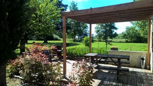 A wooden pergola with a picnic table and benches, surrounded by lush greenery and trees. - La Forestière (Monclar-de-Quercy)