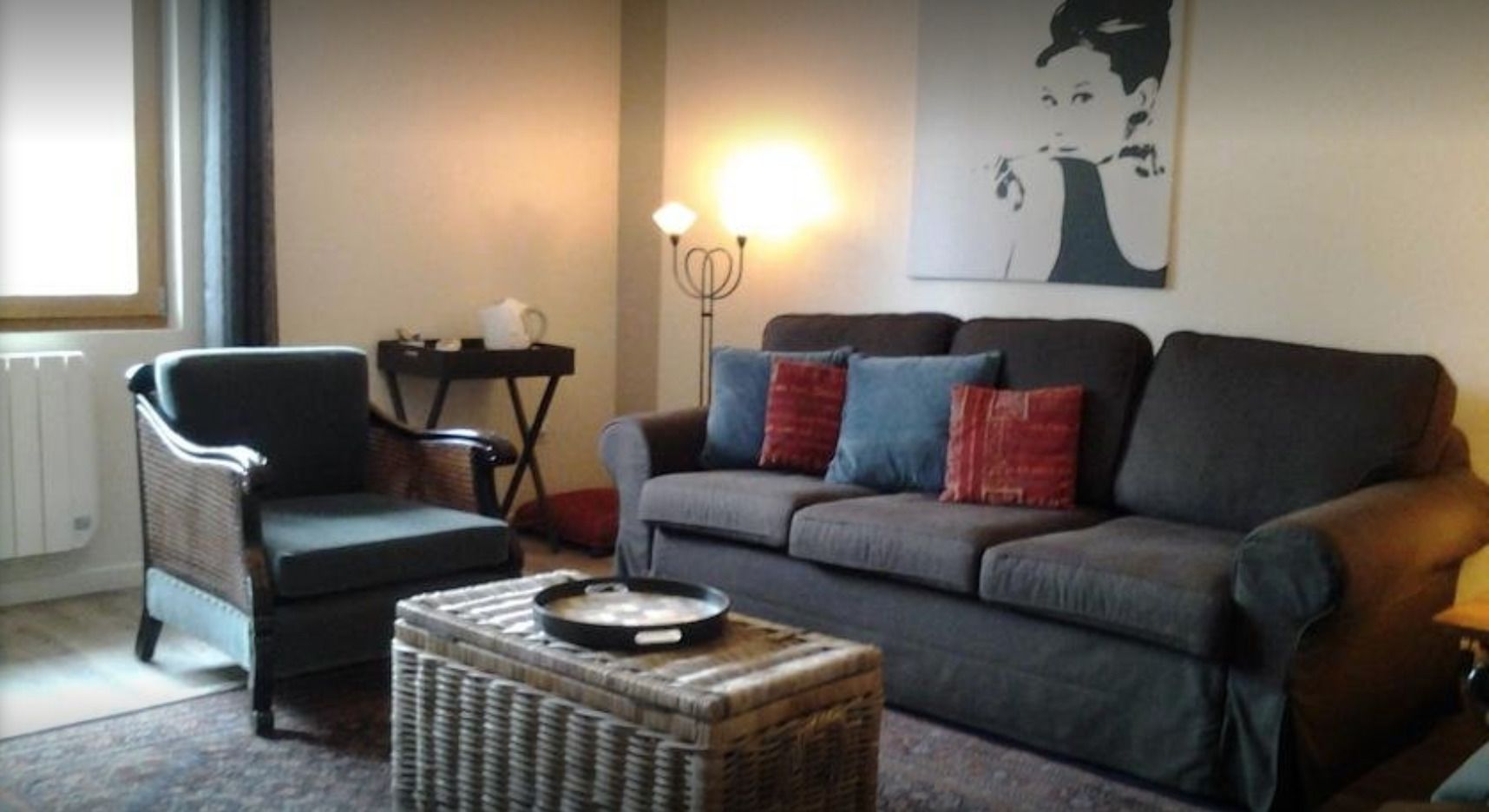 Un salon comprenant un canapé, un fauteuil et une table d’appoint avec une lampe.