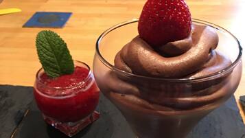 Un dessert con una fragola sopra, su una superficie di ardesia scura.