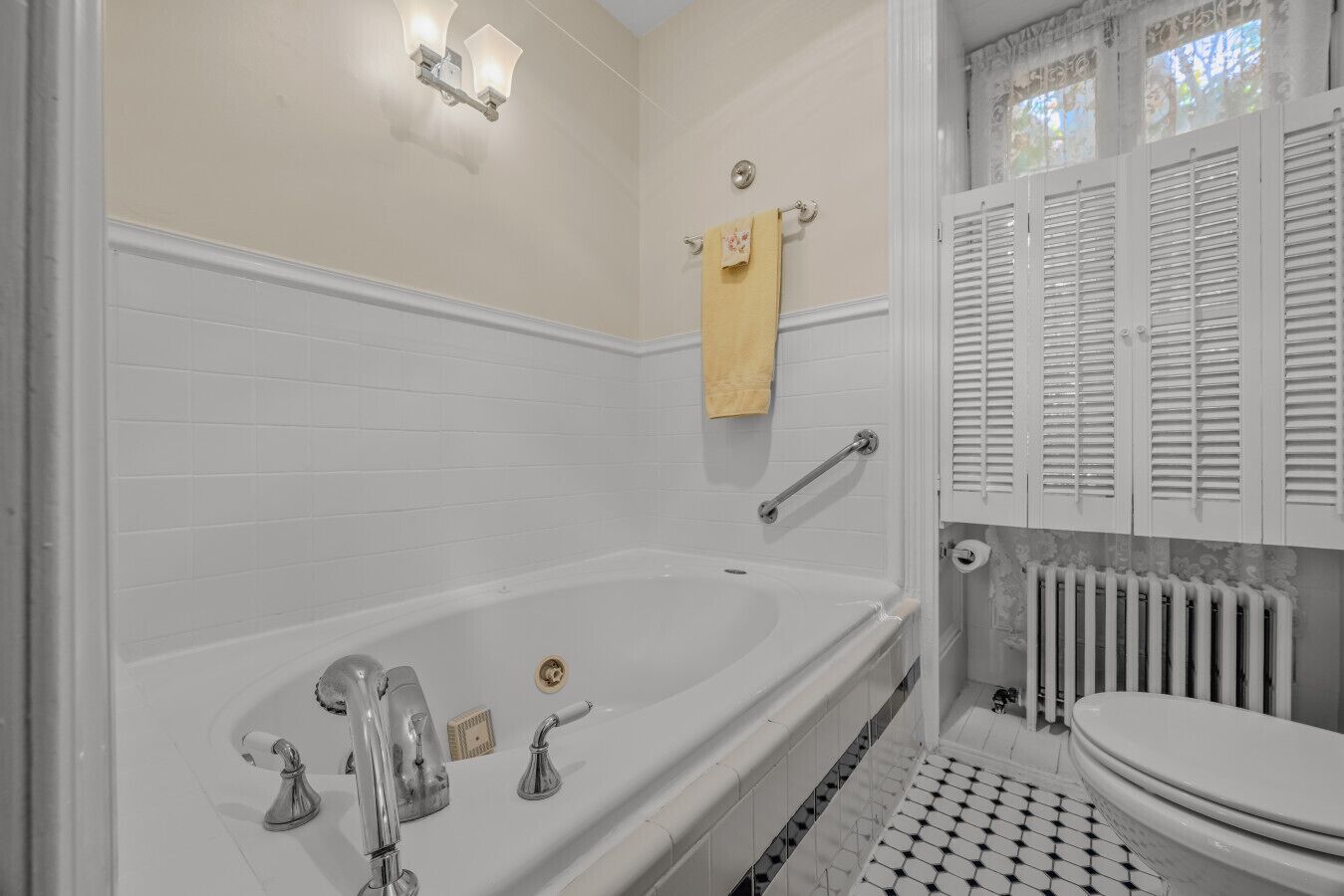 A bathroom with a bathtub, a toilet, a handrail, and a towel rack.