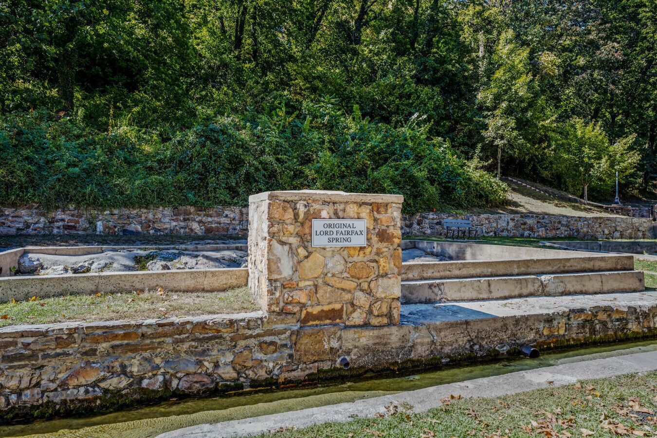 A stone sign with the text "Original Lord Fairfax Spring" in a park setting with stone steps and a water feature.