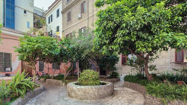 A courtyard with a stone pathway, surrounded by buildings with balconies and windows. - A. M.P. Vatican House (Roma)