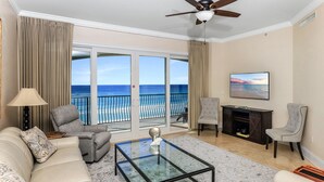A living room with a glass coffee table, two armchairs, a sofa, a TV, and a fireplace.