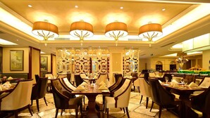 A well-lit dining area with multiple tables set for guests, featuring a decorative partition and elegant lighting fixtures.