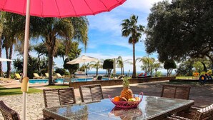 An outdoor dining area with wicker furniture, a glass table, and a fruit basket. - Beautiful Restored Algarve Typical Farmhouse, With Private Pool And Sea Views (Loulé)