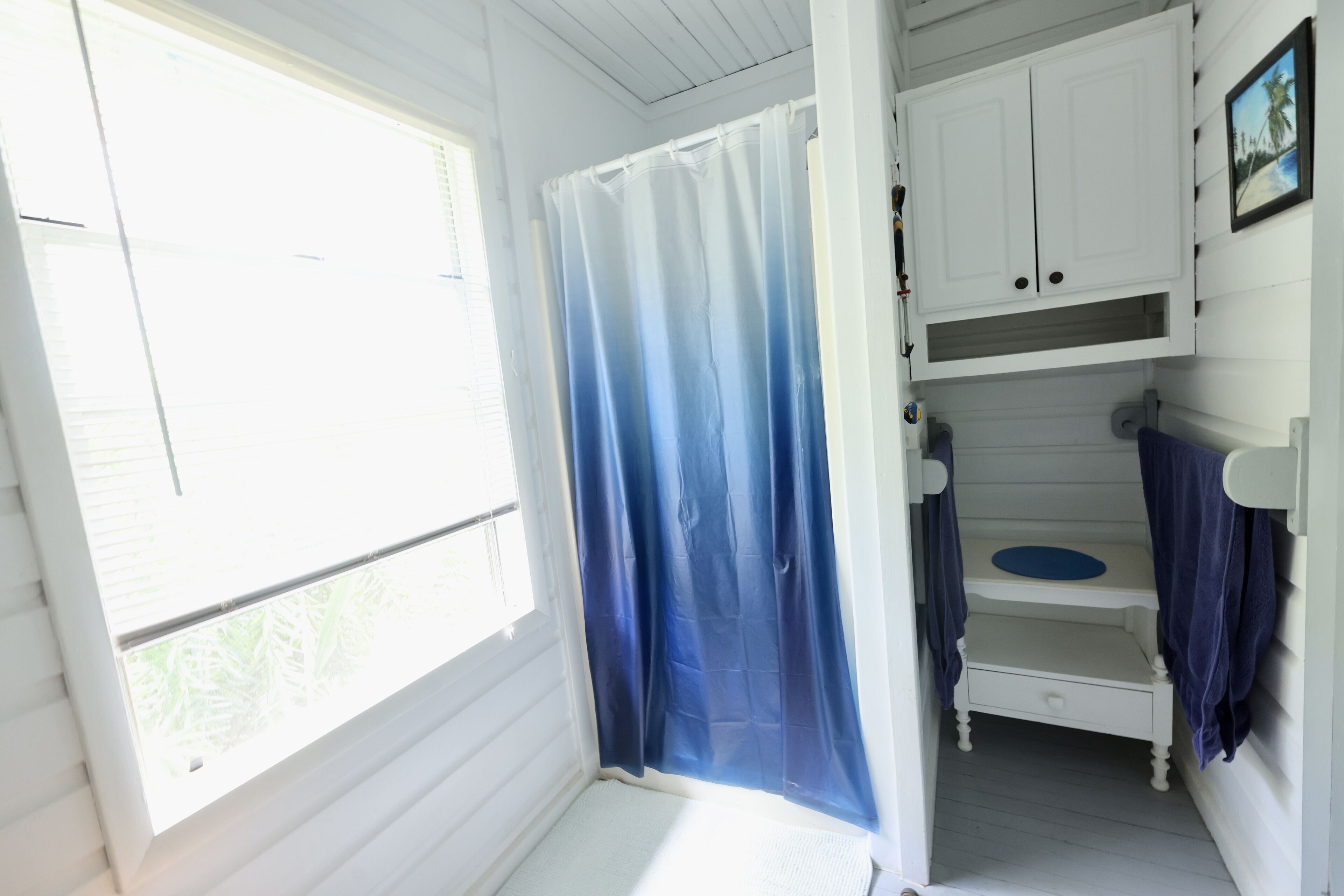 Een kleine, eenvoudige accommodatie met één kamer, een raam, een douchegedeelte en een stapelbed.
