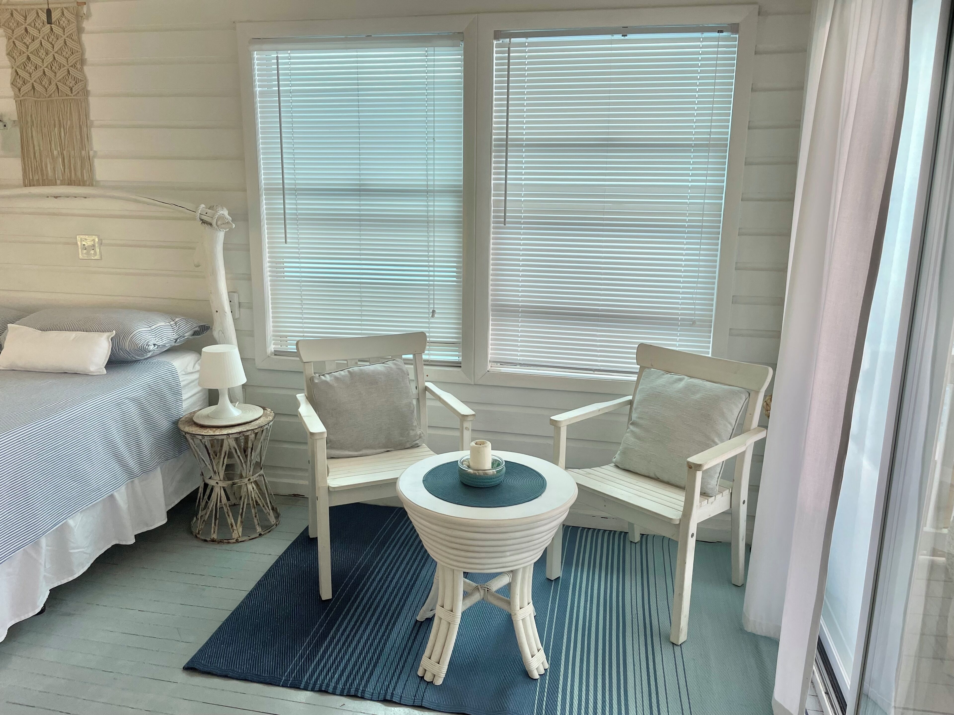 A room with a bed, two chairs, a small table, and a lamp.