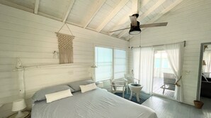 A bedroom with a bed, a ceiling fan, a window with blinds, and a view of the outside deck.
