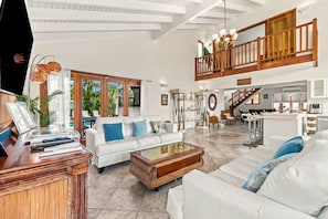 A spacious living area with a white sofa, a coffee table, and a TV on a wooden stand. - Bubali Villa - Just a 2-minute drive to Eagle Beach (Eagle Beach)
