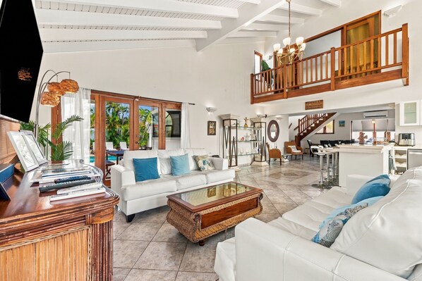 A spacious living area with a white sofa, a coffee table, and a TV on a wooden stand.