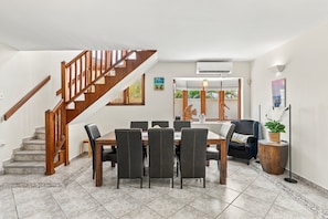 A dining area with a wooden staircase, a table with chairs, and a view of the outdoors. - Bubali Villa - Just a 2-minute drive to Eagle Beach (Eagle Beach)
