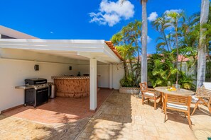 An outdoor patio with a barbecue grill, a dining table with chairs, and a covered area with a tiled floor. - Bubali Villa - Just a 2-minute drive to Eagle Beach (Eagle Beach)