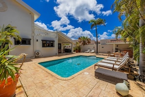 A swimming pool with lounge chairs and a patio area. - Bubali Villa - Just a 2-minute drive to Eagle Beach (Eagle Beach)