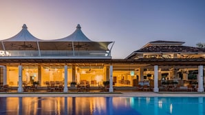 Ein Hotel mit Pool, Außenbereich und einer überdachten Terrasse mit markanter Dachkonstruktion.