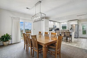 Eine moderne Küche mit weißen Schränken, einem Edelstahlkühlschrank und einem Essbereich mit Holztisch und Stühlen.