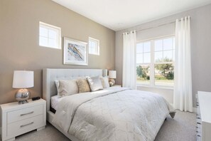 Un dormitorio con una cama grande, dos mesitas de noche con lámparas, una ventana con cortinas y una obra de arte en la pared.