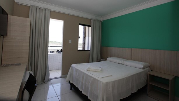 Une chambre d’hôtel équipée d’un lit, d’un bureau, d’une chaise, d’une fenêtre et offrant une vue sur l’extérieur.