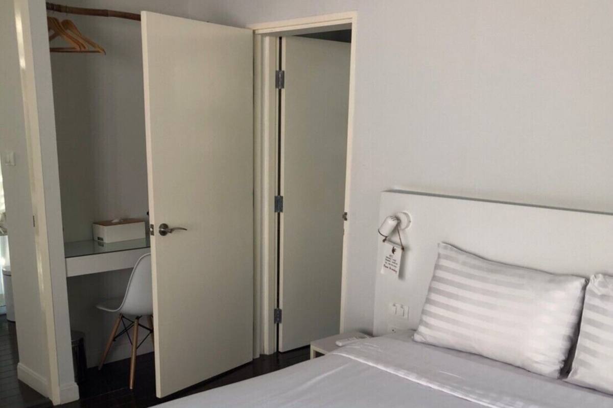 Ein Schlafzimmer mit einem großen Bett, einem Nachttisch, einem Sessel und einem Kleiderschrank.