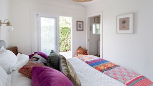 Une chambre avec un grand lit, un luminaire suspendu et une porte donnant sur un balcon.