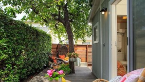 Un espace extérieur accueillant, avec une terrasse en bois, des chaises en osier et une variété de plantes en pot.