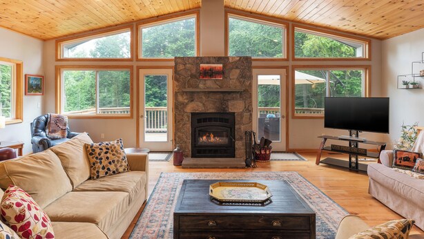 A spacious living room with a stone fireplace, large windows, and a cozy seating area.