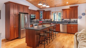 A modern kitchen with wooden cabinets, stainless steel appliances, and a central island with bar stools.
