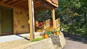 Un chalet rustique avec une façade en pierre, une véranda en bois et un espace salon extérieur.