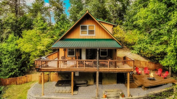 Une cabane en bois dotée d’un balcon, entourée d’arbres.