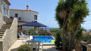Zona de piscina con una escalera de piedra, sillas de descanso y una mesa.