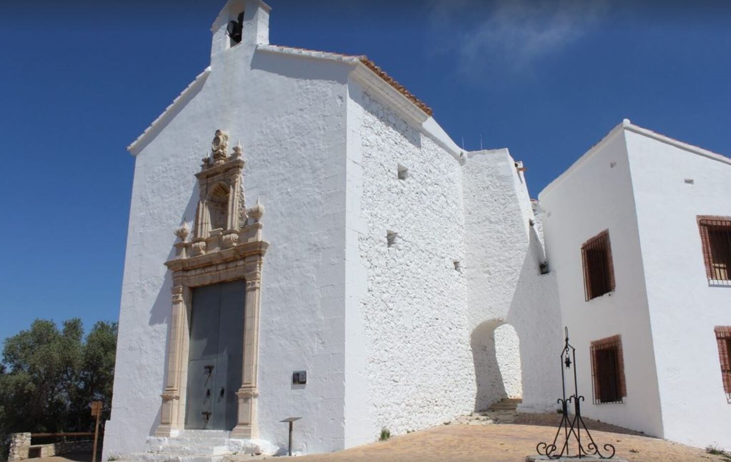 Un bâtiment blanc avec une entrée centrale, un clocher et un petit balcon.