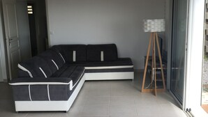 A modern living room with a sectional sofa, a floor lamp, and a sliding glass door. - Villa entre Ciel et Mer (Sainte-Anne)